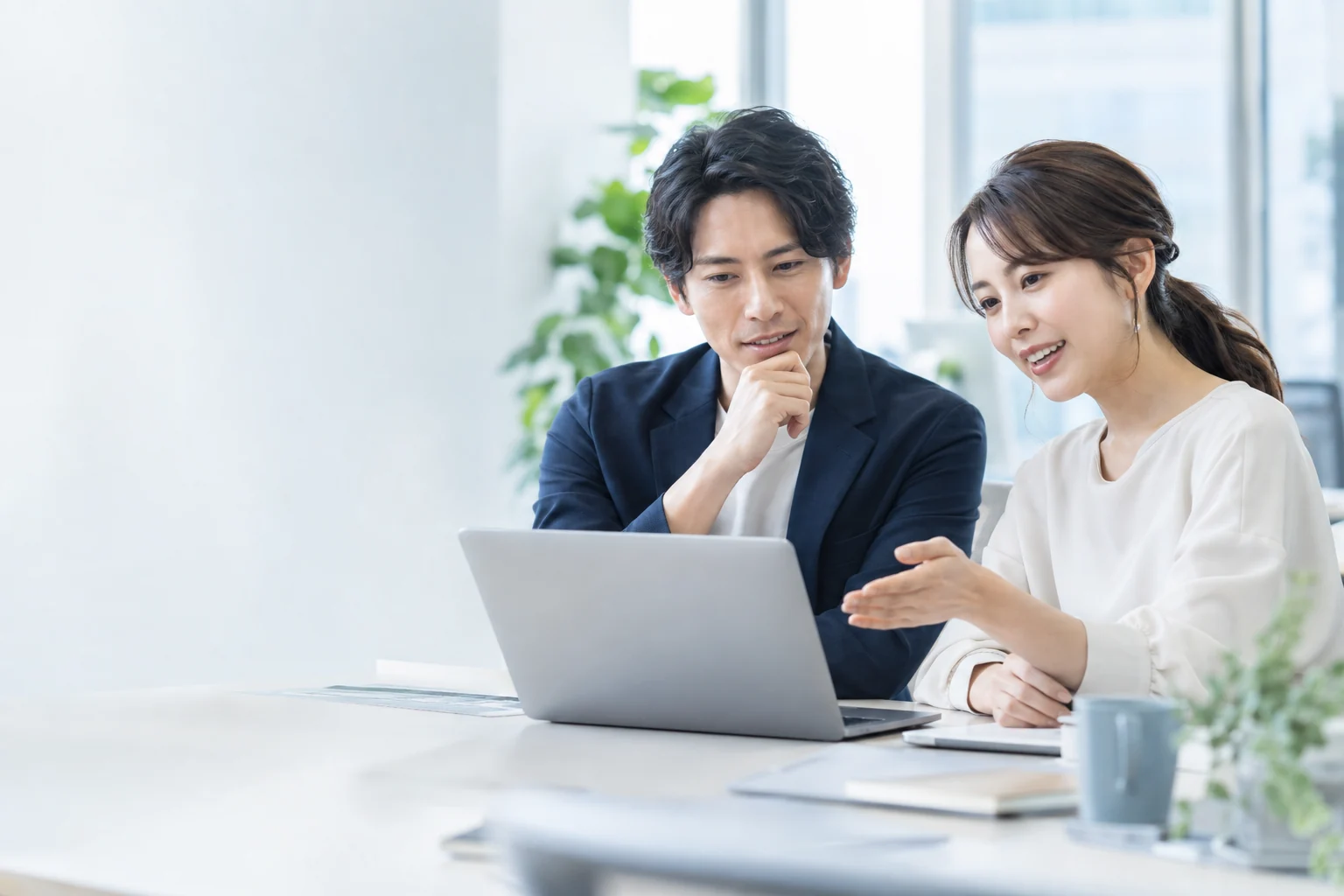明るいオフィスで受注業務を確認する二人のスタッフ